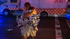 A member of the public leaves the scene with her child, who is covered in an emergency blanket, after a shooting at Bondi Beach on December 14, 2025 in Sydney, Australia