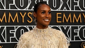 A Black woman smiles in front of a bcakdrop for the Emmys